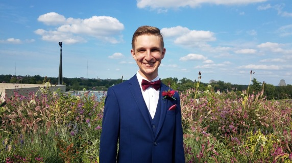 Joe Beggs ’19 wears a suit and stands in a field