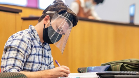 Masked students study in a classroom