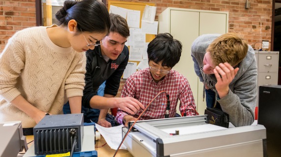 4 students conduct physics lab