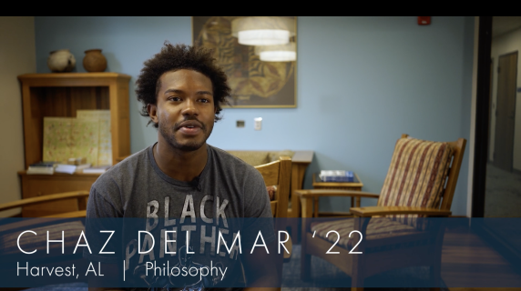 Chaz Del Mar '22, Philosophy major from Harvest, AL, sit in a well-lit student study space. Behind him are lounge chairs, a desk with pottery, and an art piece that reflects one of the lights.