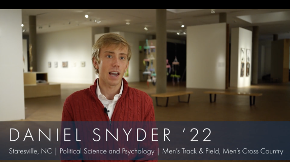 Daniel Snyder '22, Political Science and Psychology major from Statesville, NC and a member of Men's Track & Field and Cross Country, stands and looks at the camera. Behind him are multiple art displays from Grinnell's Museum of Art.