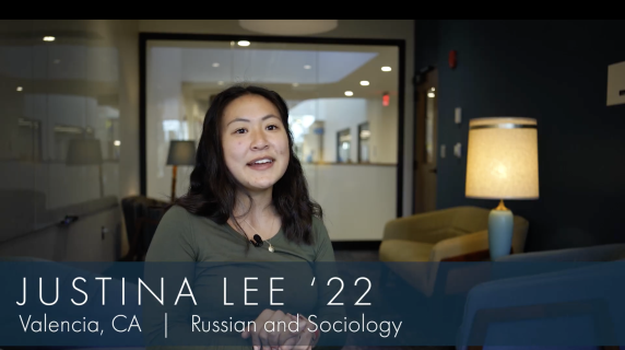 Justina Lee '22, Russian and Sociology major from Valencia, CA, sits in one of the study spaces on campus. Behind her are well-lit lamps, lounge chairs, and a glass window that reveals the humanities building's hallways.