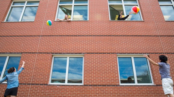 Students playing with beach balls near a dorm