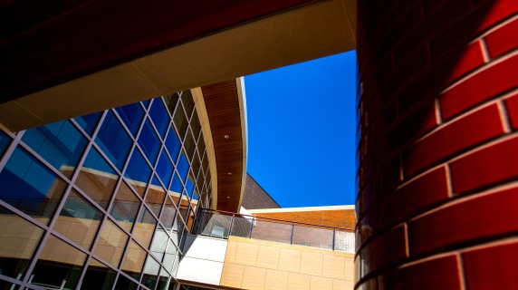 An abstract angle of the Joe Rosenfield Center. On the left, a glass, gridded wall and on the right, a close up of a red bricked pillar.