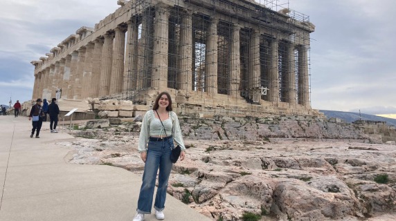 Kalea stands happily next to a Greek monument.
