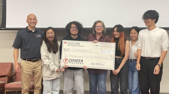 Team of students with their big check prize, with event judge and host