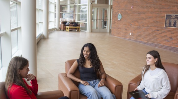 a coach meets with two students in a building lobby