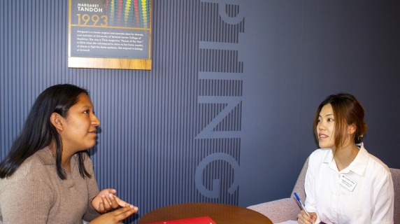 two women interact in a seated interview setting
