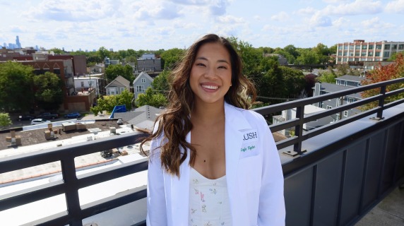Photo of Kayla Figatner in a white doctor's coat on the roof of a building