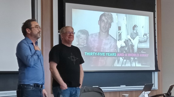 slideshow with photos in background, an instructor introduces a guest speaker. 