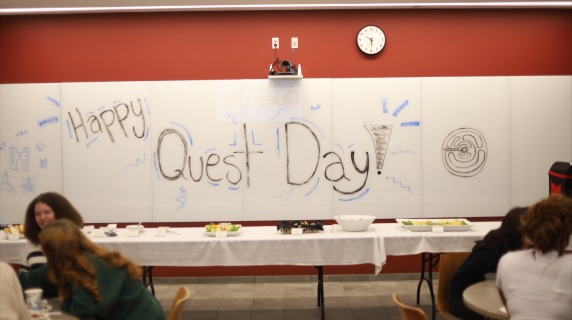 white board reads "Happy Quest Day"