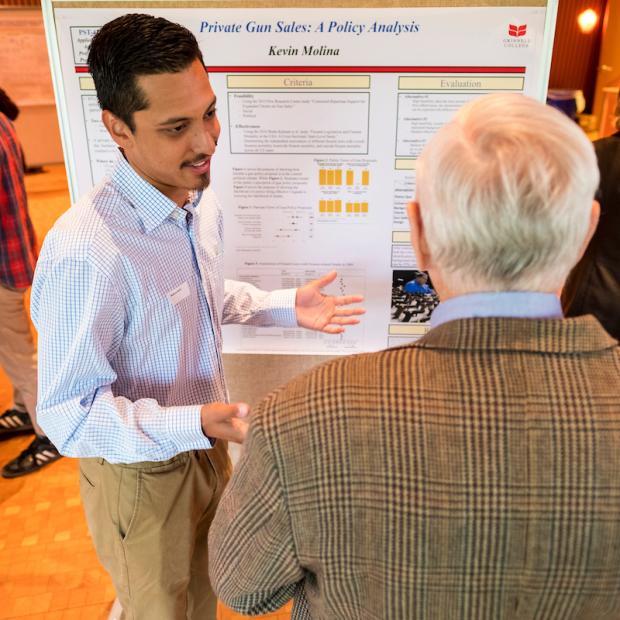 student presents research poster to faculty
