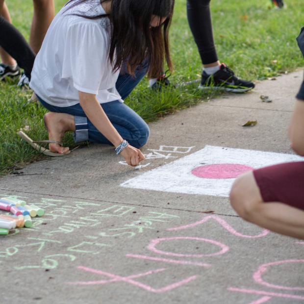 Students write chalk messages on sidewalks