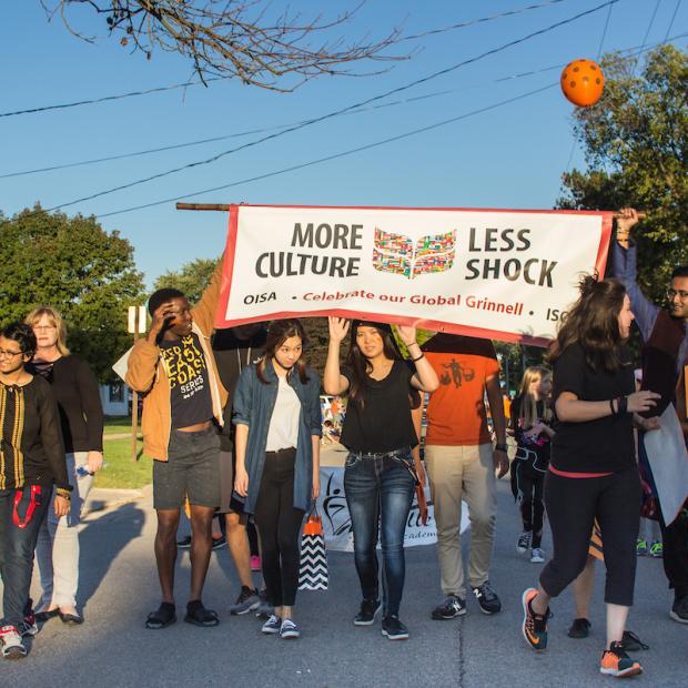 students hold parade banner "More Culture, Less Shock"