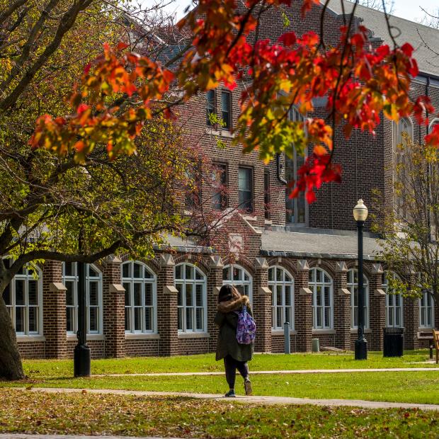 student walks near South Campus residence halls, autumn leaves in foreground