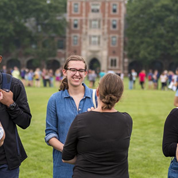 Students stand in circle and chat on MAC field