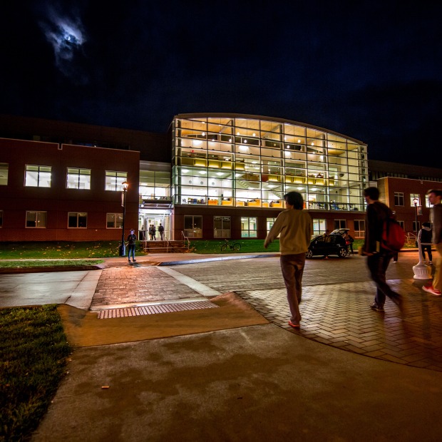 Students heading to a brightly lit Noyce Science Center at night