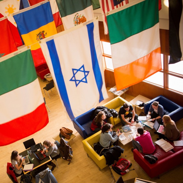 Students chat together under the global flags in Spencer Grill