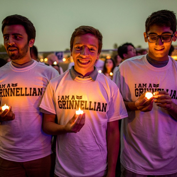 Three students hold candles outdoors at dusk