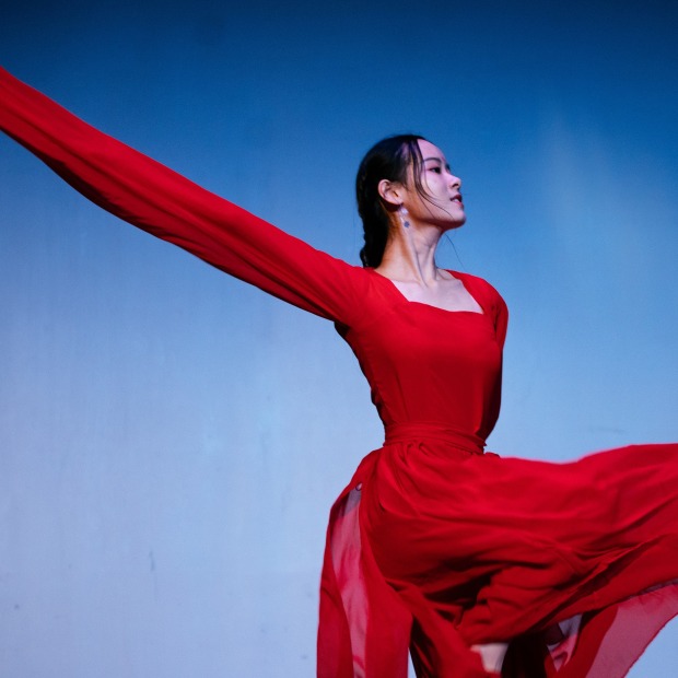 A woman dances in a long and flowing red dress.
