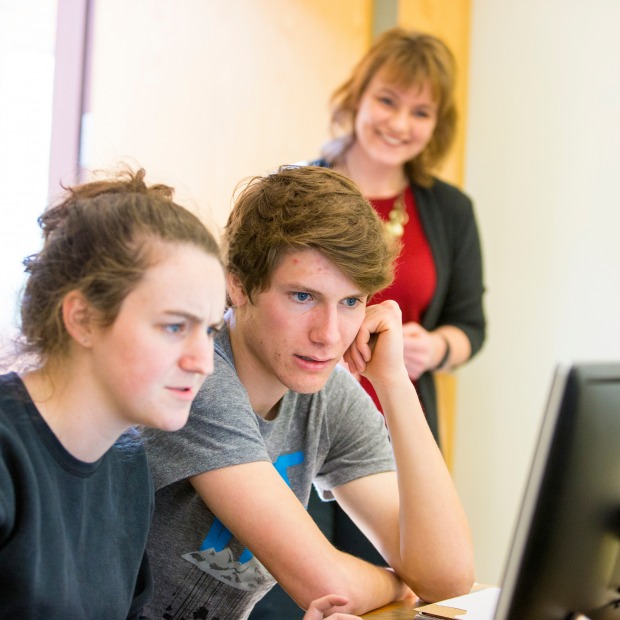 Two students work at a computer together while Professor Shonda Kuiper observes