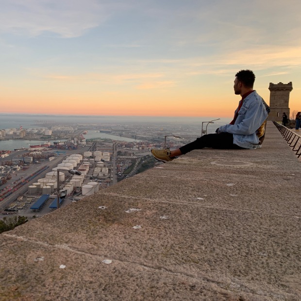 Max Hill sitting on a wall at Castle Montjuic, Barcelona, Spain, at sundown
