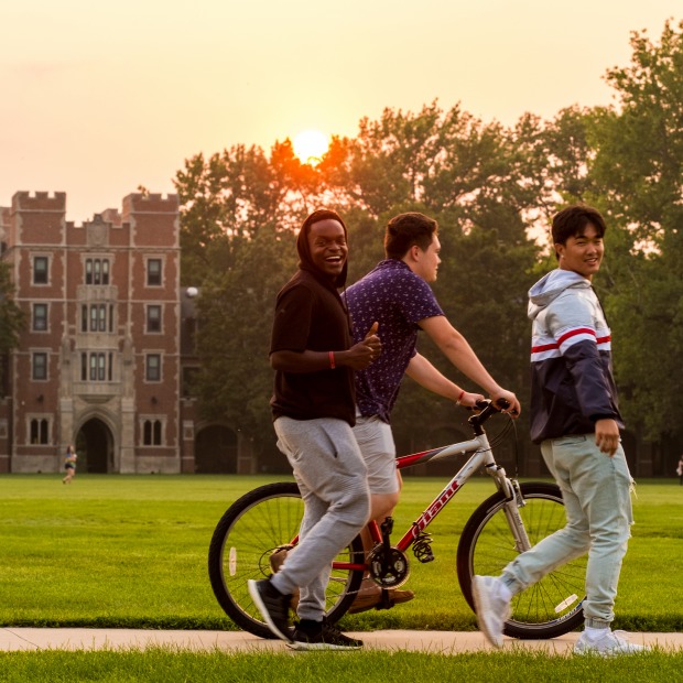 Students walking and biking through mac field