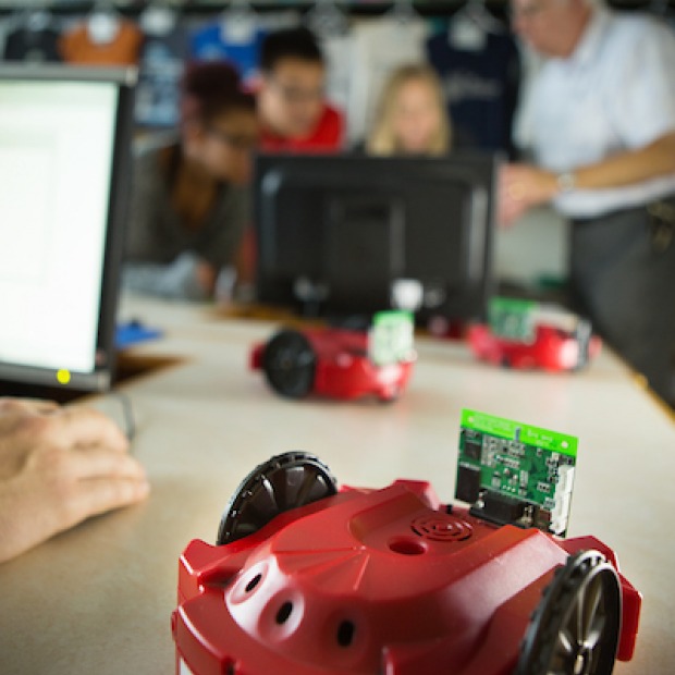 Small robot observed by group of students and faculty