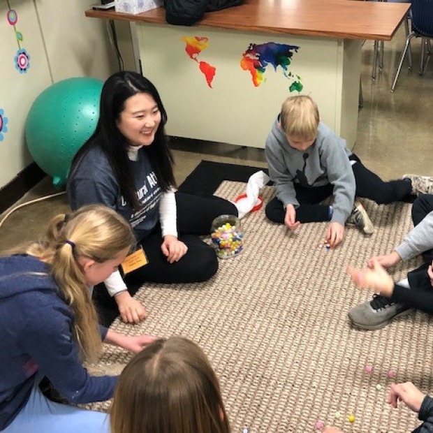 Shirley Jwa playing gonggi with Grinnell Middle School students