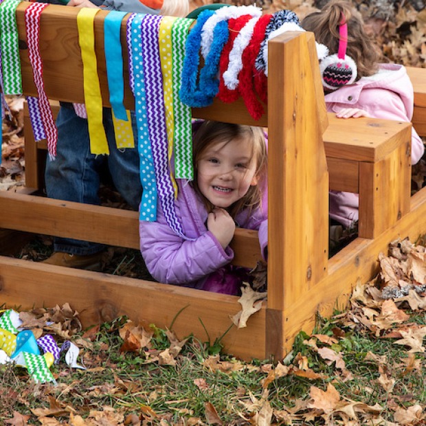 smiling child peeks out from hanging ribbons