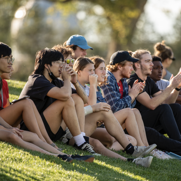 Students sit on a grassy hill