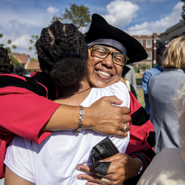 Two people in graduation attire embrace