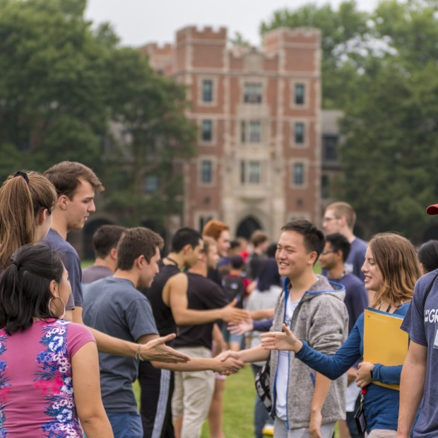 Students shaking hands in front of Gates Tower
