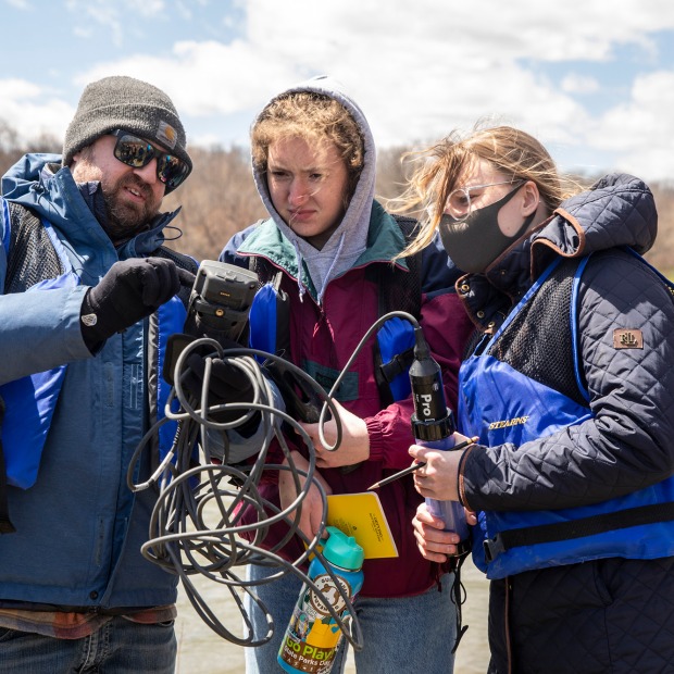 professor and 2 students handle equipment for aquatic geochemistry