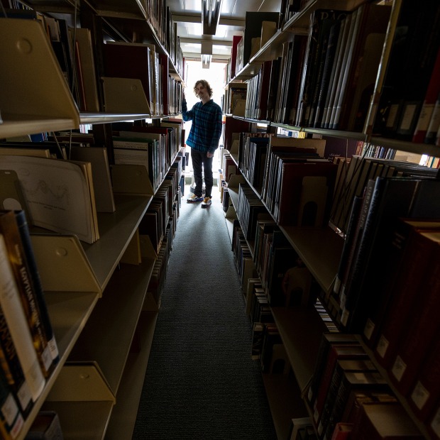 Daniel Rosenbloom stands in the library stacks surrounded by books
