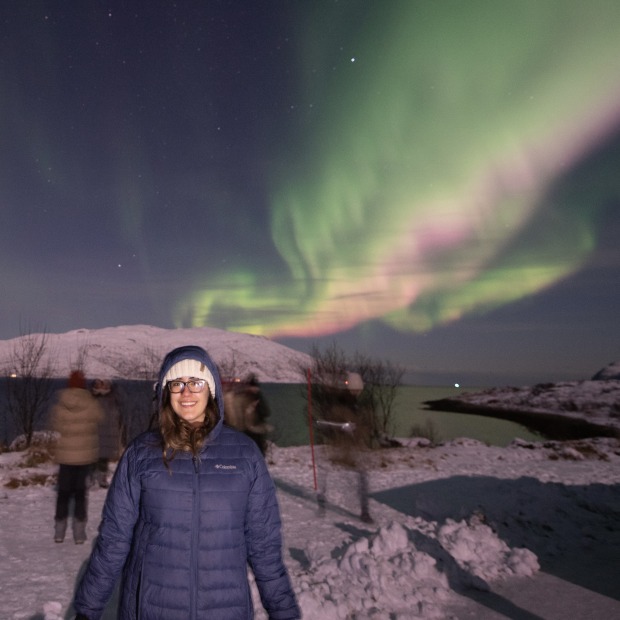 Andrea Suazo Rivas standing in the snow with the Northern Lights above her
