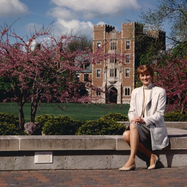 Pamela Ferguson sitting on short wall with North Campus in background