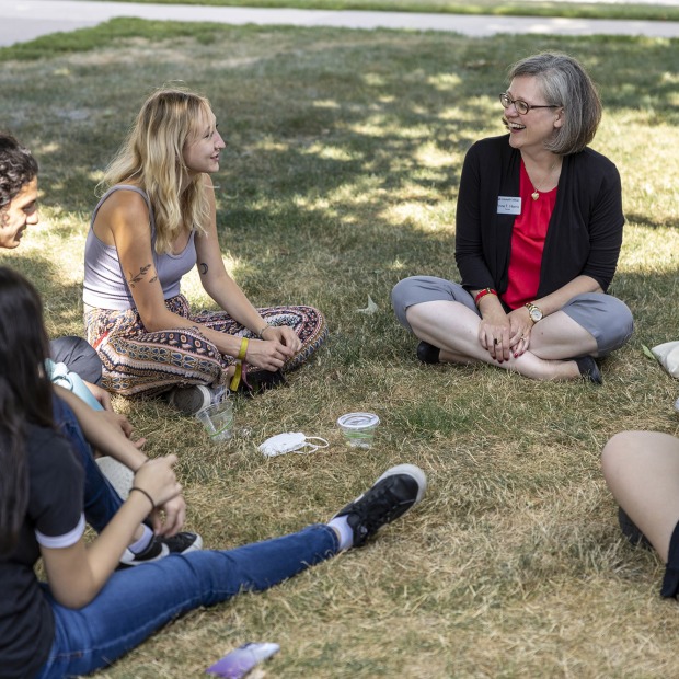Anne Harris and a circle of students sit on the lawn talking together