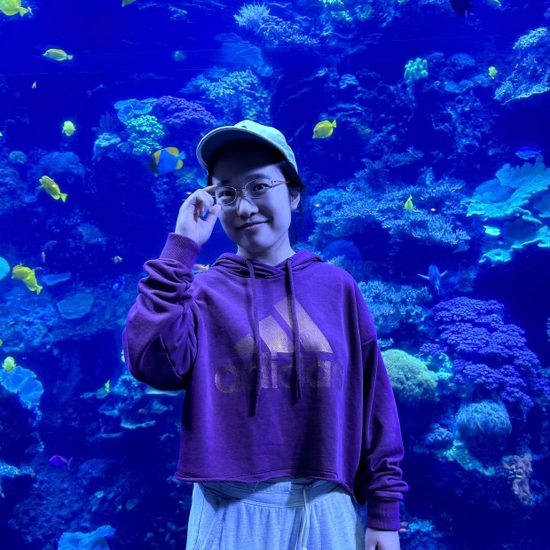 Lydia Hong in front of an aquarium with fish 