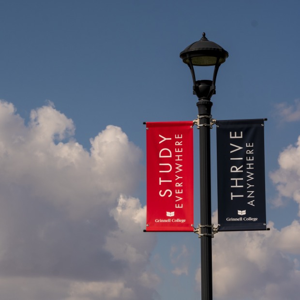 2 flags on a college campus against a blue sky