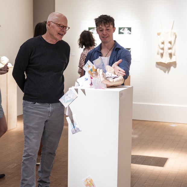 a professor and student speak in an art gallery