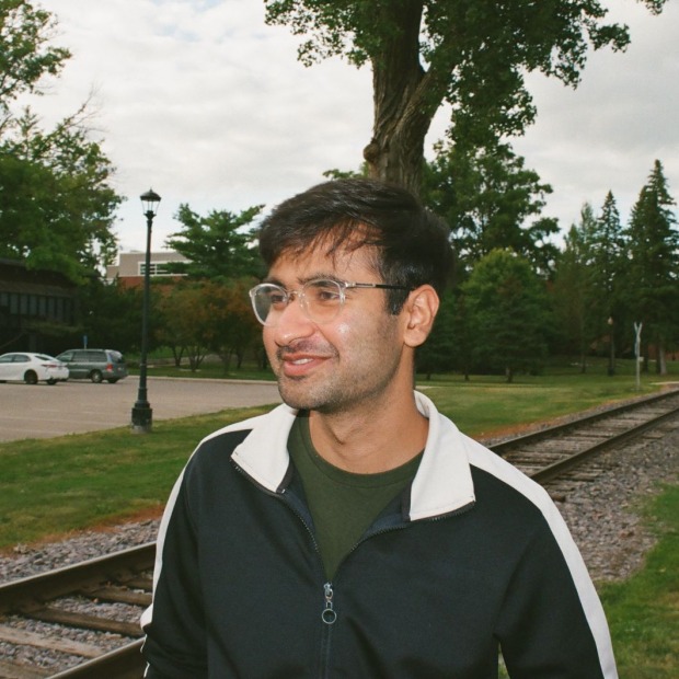 Arsal standing near a train track smiling into the distance