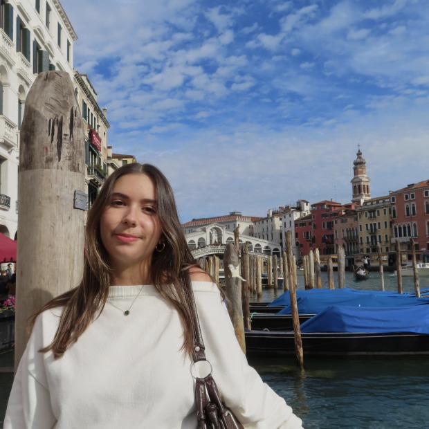 Beatriz stands next a river smiling at the camera