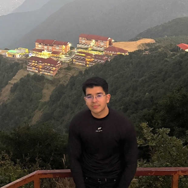 Farhan smiles at the camera with a mountainous view in the background