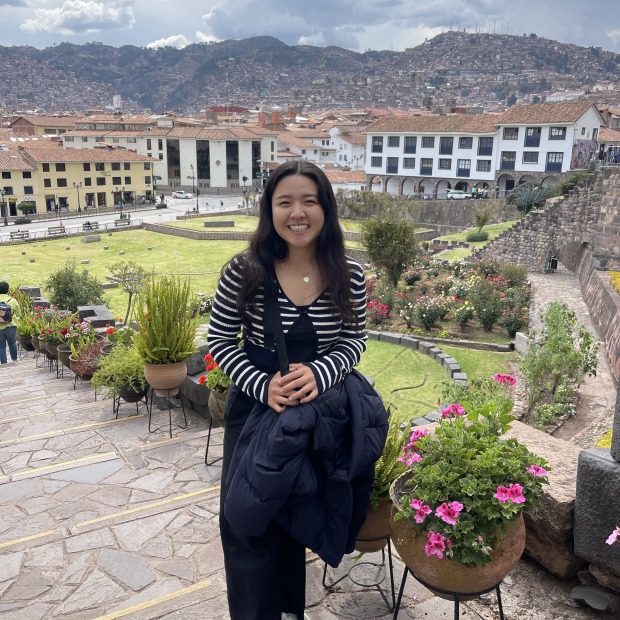 Meilin smiles at the camera with a village in the background