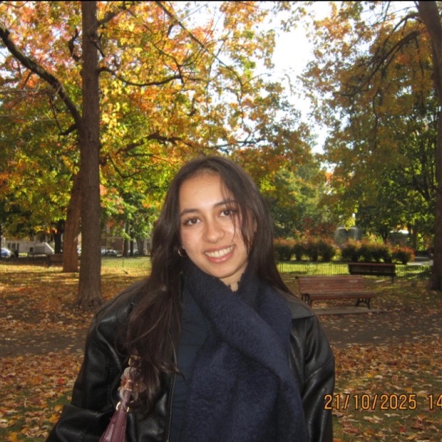 Rabbani smiles at the photographer with autumn trees behind her