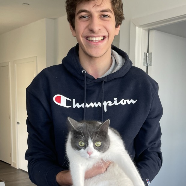 Jafar smiles at the camera holding a white cat