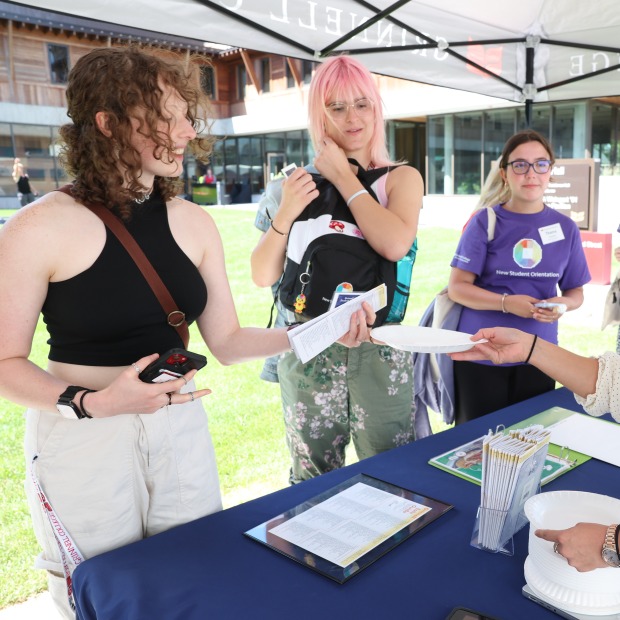 Excited new students at a check-in table during orientation