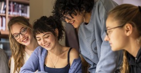 Four Grinnell College art history students at a table examining artwork in the Iowa Room of the Drake Community Library in Grinnell. 