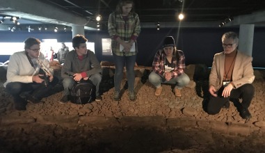 Students crouching in the dirt at The Settlement Exhibition